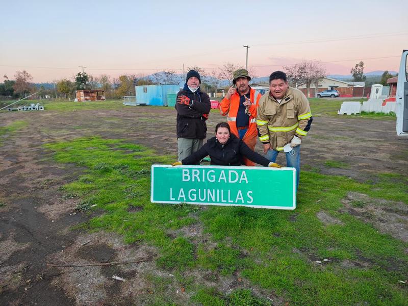 Voluntarios sosteniendo el letrero de la Brigada Lagunillas en el terreno
